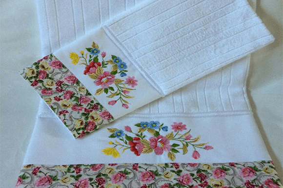 Elegant floral embroidery design on white towels with colorful flower patterns.