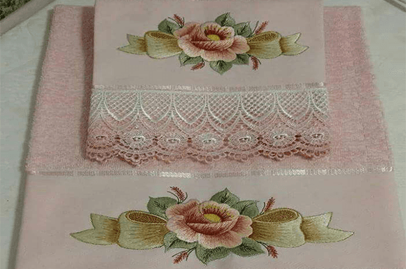 Elegant single rose embroidery design with ribbon accents on pink fabric.