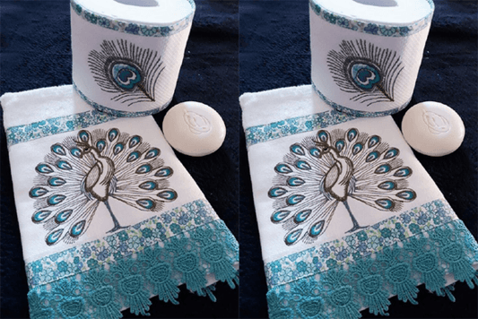 Elegant peacock embroidery design on a white towel with teal lace trim, paired with a matching embroidered toilet paper roll and soap.