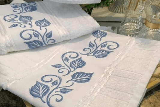 Elegant blue leaf embroidery design on white towels for decor.